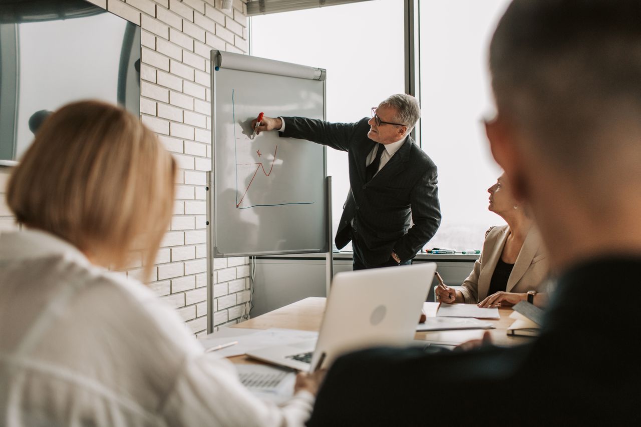 A focused business team engaging in a meeting with a presentation on a whiteboard.